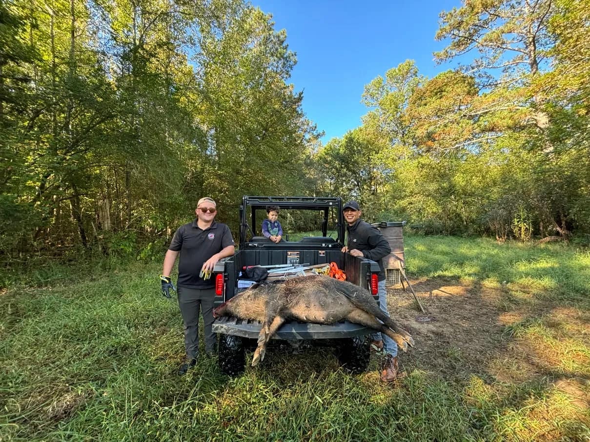 Hunting group with a utility vehicle and a harvested wild hog in South Carolina woodland